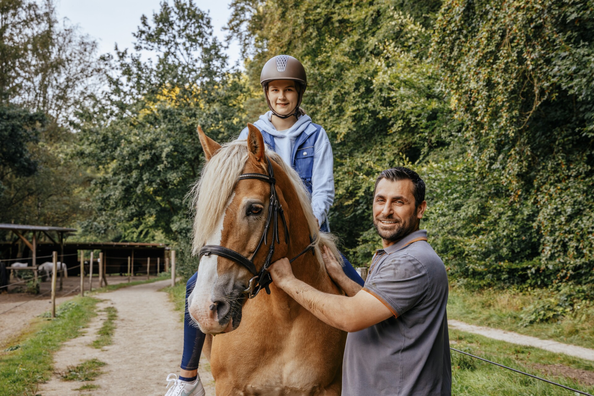 Foto: Person hilft Kind beim Reiten