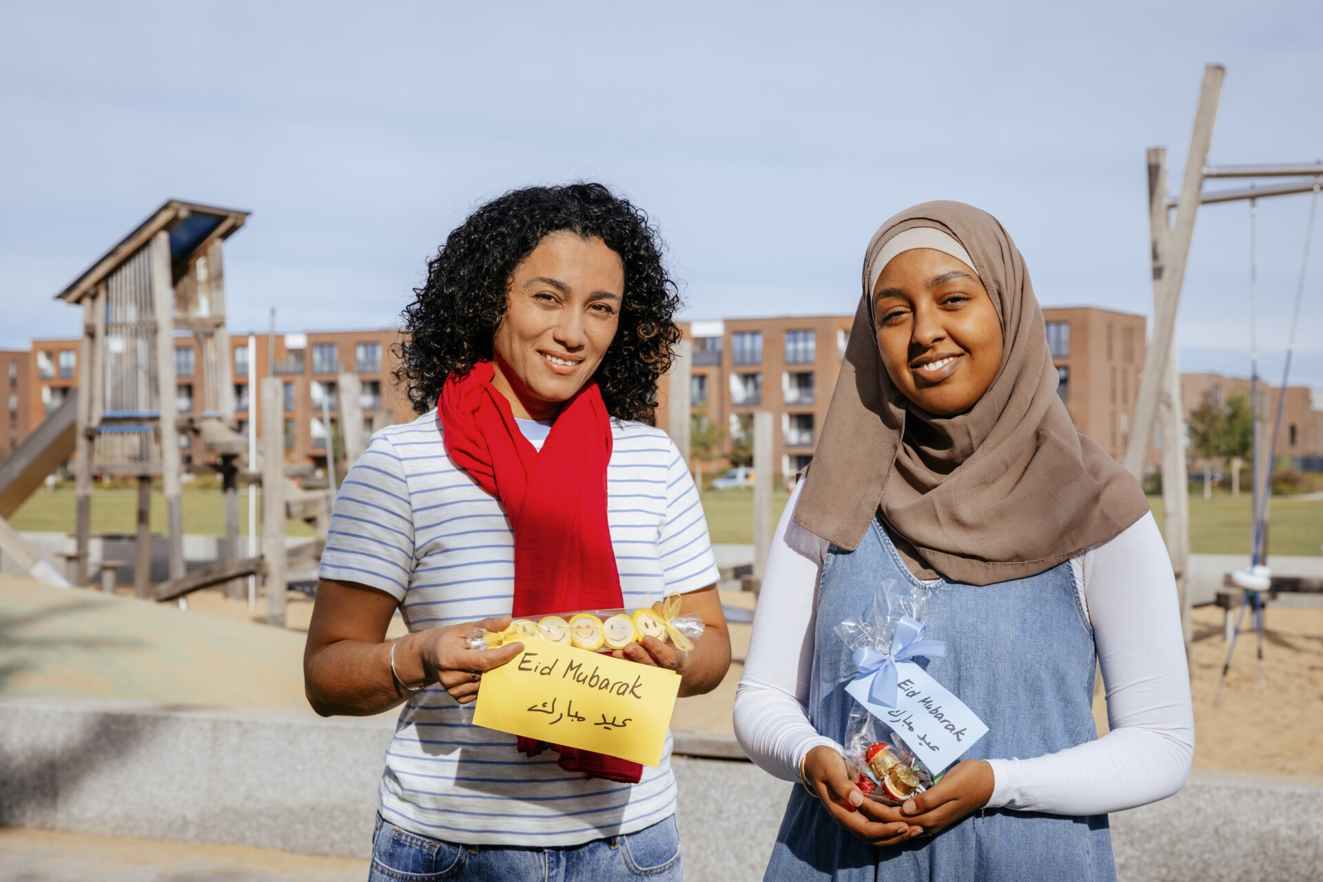 Foto zwei Personen lächeln in die Kamera und haben Ramadan Geschenke in der Hand